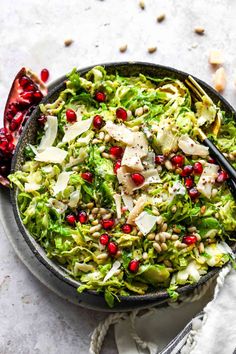 a bowl filled with shaved brussels sprouts and topped with pomegranate