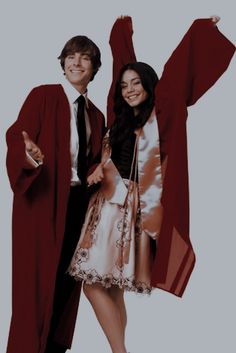 two people dressed in graduation gowns posing for a photo with one holding his arms up