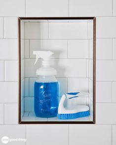 a bathroom mirror with a blue bottle and cleaning brush in it next to a white tile wall