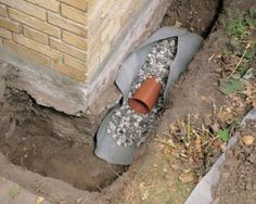 a pair of shoes that are sitting in the ground next to a brick wall and some dirt