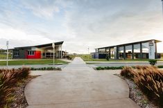 an empty walkway leading to two buildings with red doors on each side and grass in the foreground