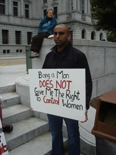 a man holding a sign that says being a man does not give me the right to control women