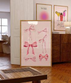 two framed pictures with pink bows hang on the wall in front of a wooden table