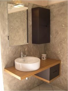 a bathroom sink sitting under a mirror on top of a wooden counter next to a cabinet