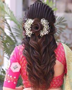 the back of a woman's head with long hair and flowers in her hair