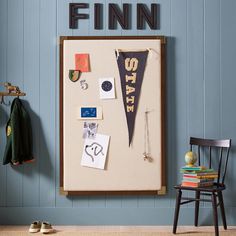 a bulletin board with the word finn on it next to a chair and coat rack