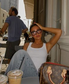 a woman sitting at a table in front of a window with her hand on her head