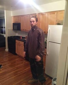 a man standing in a kitchen next to a refrigerator freezer and stove top oven