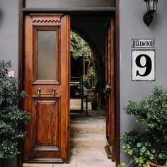 an entrance to a house with potted plants on either side and the door open