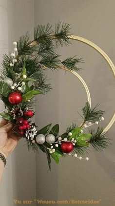 a person holding a wreath with christmas decorations on it