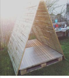 a wooden structure sitting on top of a lush green field next to a picnic table