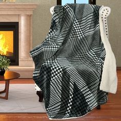 a black and white blanket sitting on top of a chair next to a fire place