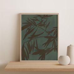 a white vase sitting on top of a wooden shelf next to a green painting with leaves