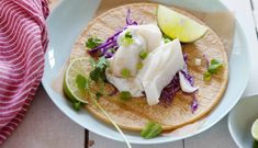 fish tacos with cabbage and limes on a plate