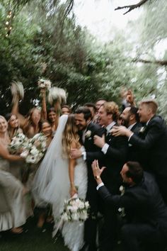 a group of people standing around each other in front of a bride and groom on their wedding day