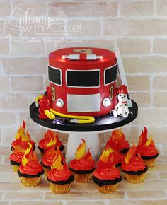 a fire truck cake and cupcakes on a table