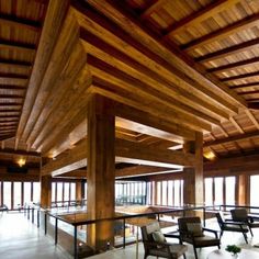 the inside of a building with wooden beams and tables, chairs, and couches