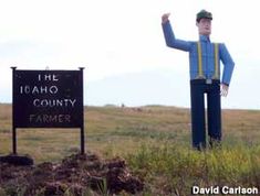 a man standing next to a sign in the middle of a field