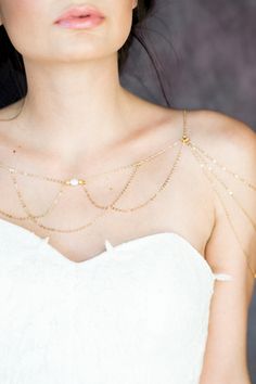 a woman in a white dress wearing a gold chain necklace