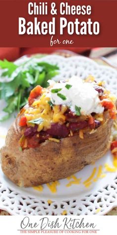 a baked potato topped with cheese and other toppings on a white plate next to greens