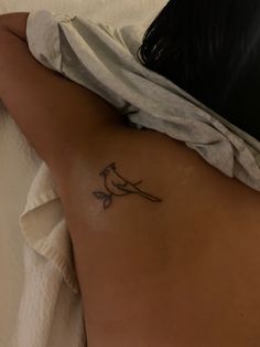 a small bird tattoo on the back of a woman's left side ribcage