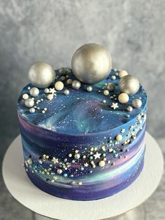 a blue and purple cake with silver balls on top