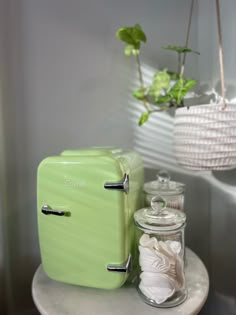 a green refrigerator sitting on top of a table next to a jar filled with sand