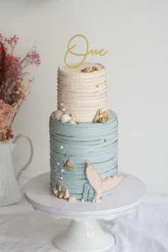 a blue and white cake sitting on top of a table next to a vase with flowers