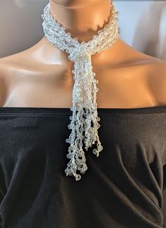 a woman wearing a white crochet scarf on top of a mannequin