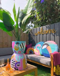 an outdoor seating area is decorated with colorful pillows and throw pillows, along with a welcome sign