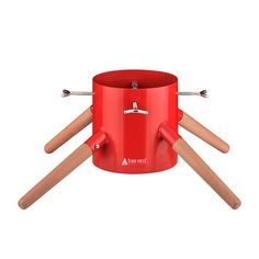 a red camping pot with four wooden sticks sticking out of it's top and bottom