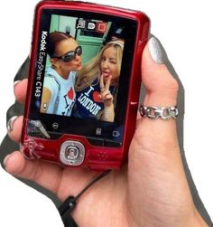 a person holding up a cell phone with two pictures on the screen and one being held in their hand