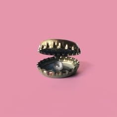 two metal objects sitting on top of a pink surface with one object in it's mouth