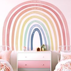 a child's bedroom decorated in pastel colors with a rainbow wall decal