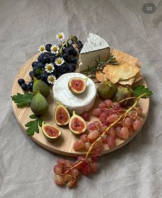 a wooden plate topped with grapes, cheese and figurines next to crackers