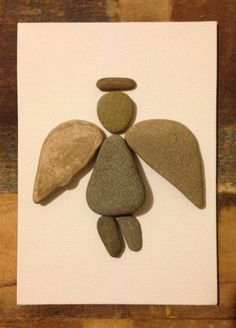 an angel made out of rocks sitting on top of a piece of paper