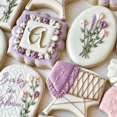 some decorated cookies are laying out on a white table top with purple and pink icing