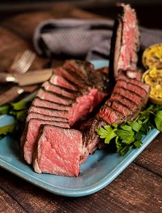 steak and greens on a blue plate with silverware