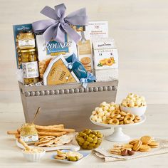 a gift basket filled with cheese, crackers and olives next to other snacks