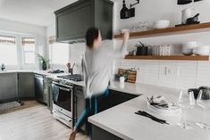 a person standing in a kitchen next to a stove top oven