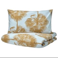 two pillows with palm trees on them, one is blue and the other is yellow