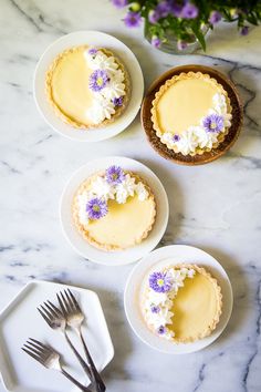 three small pies with flowers on them are sitting on plates next to each other