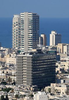 an aerial view of a city with tall buildings and the ocean in the back ground