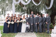 a group of people standing next to each other in front of a white arch covered with trees