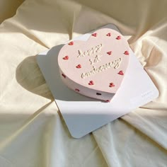 a heart shaped cake sitting on top of a white plate next to a pink box