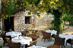 an outdoor dining area with wicker chairs and tables covered in white tablecloths