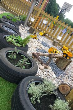 there are many tires that have plants in them on the grass and some rocks next to each other