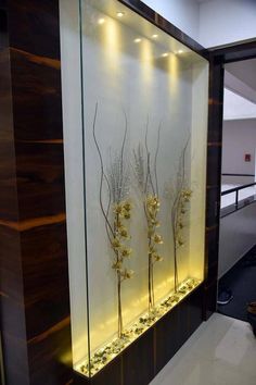 three glass vases with flowers in them are on display against a white and brown wall