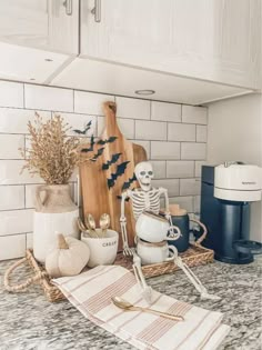 a kitchen counter with skeleton figurines, cutting board and utensils on it