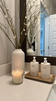 a white vase sitting on top of a bathroom counter next to a candle and some bottles